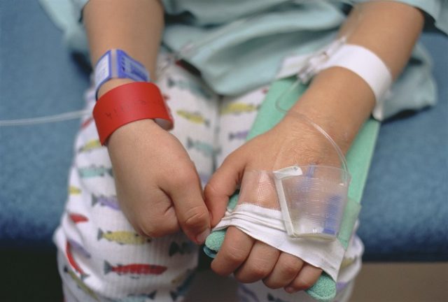 Young boy in hospital bed showing intravenous lines in arm